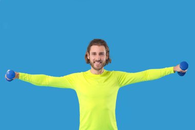 Mavi arka planda dambılları olan sportif adam.