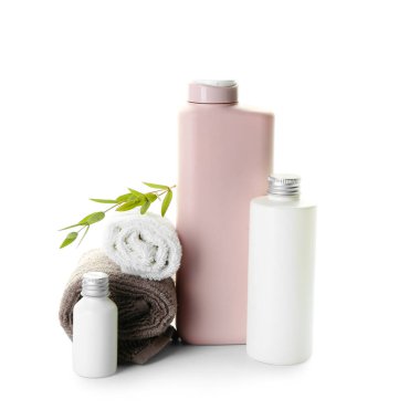 Beyaz arka planda şişeler dolusu kozmetik ürünler ve temiz havlular