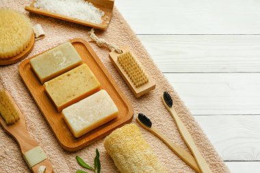 Hafif ahşap arka planda sabunlu banyo malzemeleri seti, yakın plan.
