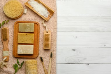 Hafif ahşap arka planda sabun kalıplı banyo malzemeleri.