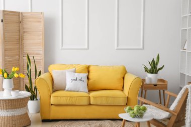 Sarı kanepesi ve masaları olan modern oturma odası.