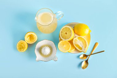 Renkli arkaplanda olgun limonlar, meyve suyu ve sürahi ile kompozisyon