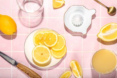 Olgun limonlu kompozisyon, seramik sıkacağı ve renkli fayansların üzerine bir bardak meyve suyu.