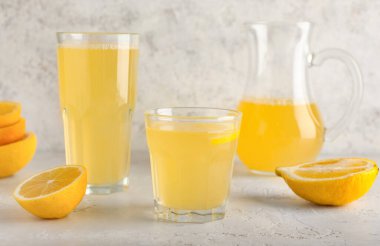 Açık arkaplanda taze limon suyu olan bardaklar.