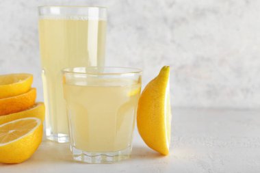 Açık arkaplanda taze limon suyu olan bardaklar.