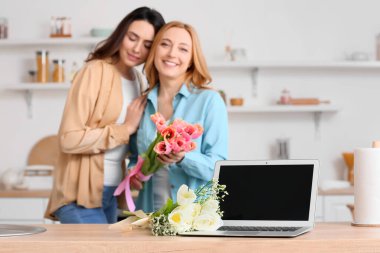 Laptop ve çiçek buketi mutfaktaki masada.