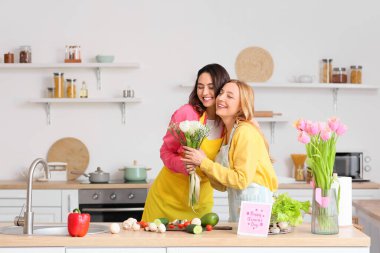 Genç bir kadın mutfakta Uluslararası Kadınlar Günü için annesini selamlıyor.