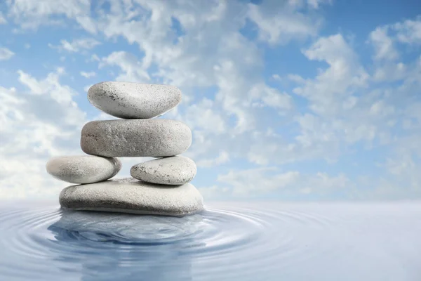 stock image Stack of spa stones in water against cloudy sky