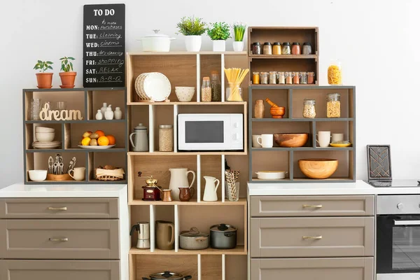 Mutfak iç kısmında mutfak aletleri ve modern mikrodalga fırını olan raf ünitesi.