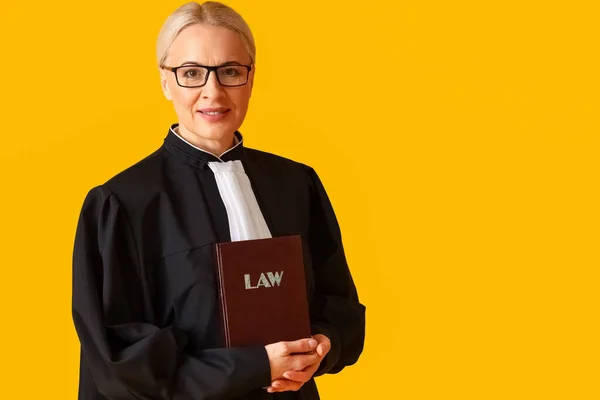 Sarı Arka Planda Hukuk Kitabı Olan Yetişkin Kadın Yargıç — Stok fotoğraf