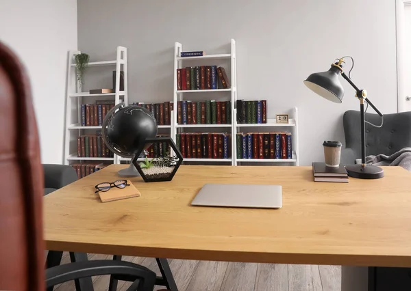 Ev kütüphanesinde modern dizüstü bilgisayarı olan şık bir iş yeri