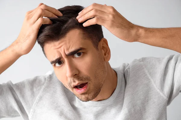 Hafif arka planda saç kaybı sorunu olan endişeli genç adam, yakın plan.