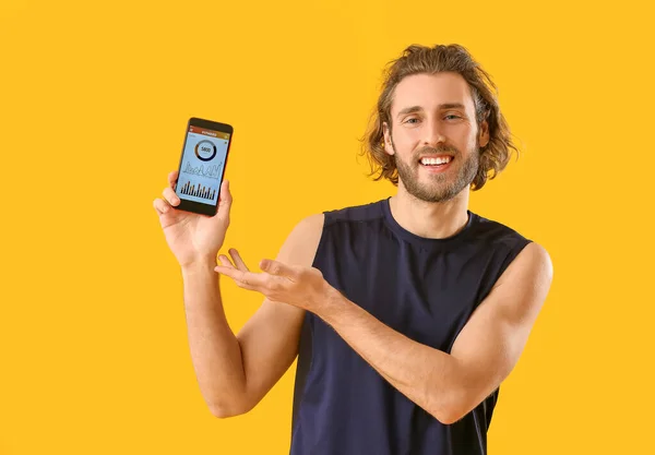 Sportowy Mężczyzna Trzyma Telefon Zainstalowaną Aplikacją Kalorie Licząc Kolorowe Tło — Zdjęcie stockowe