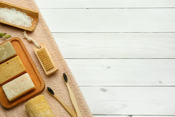 Hafif ahşap arka planda sabun kalıplı banyo malzemeleri.