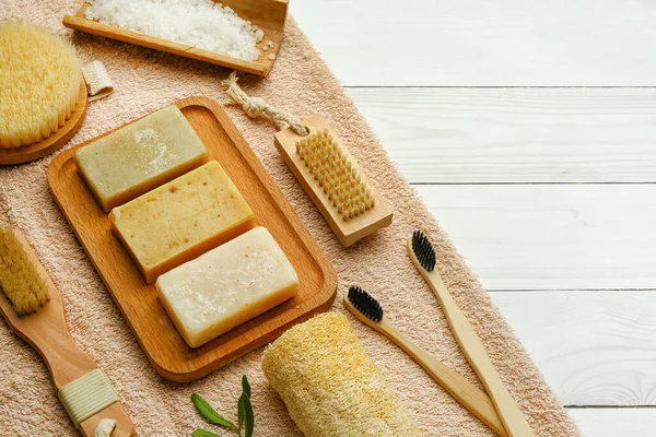 Hafif ahşap arka planda sabunlu banyo malzemeleri seti, yakın plan.
