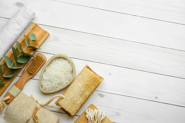 Hafif ahşap zemin üzerinde deniz tuzu bulunan banyo malzemeleri.