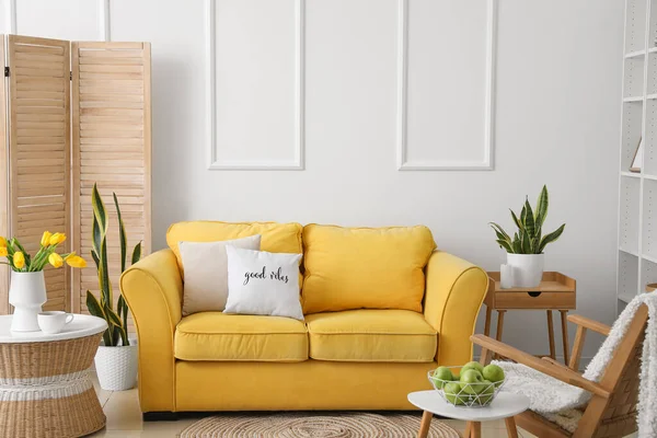 Sarı kanepesi ve masaları olan modern oturma odası.