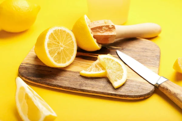 Tahta tahta tahta, limon sıkacağı ve sarı arka planda bıçak, yakın plan.