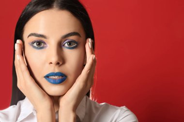 Kırmızı arka planda yaratıcı makyajı olan güzel genç bir kadın.