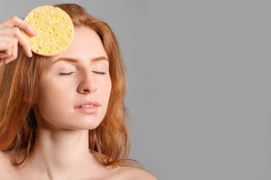 Gri arka planda makyaj süngeri olan güzel bir kadın.