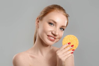 Gri arka planda makyaj süngeri olan güzel bir kadın.