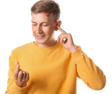 Beyaz arka planda kulak tıkacı olan yakışıklı bir genç.