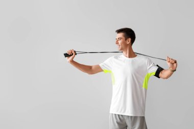 Gri arka plan üzerinde ip atlama ile sportif genç adam