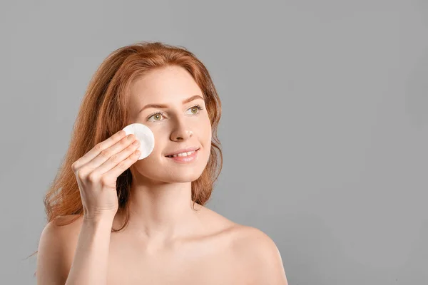 Beautiful woman with makeup sponge on grey background