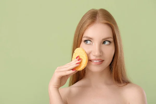 Beautiful woman with makeup sponge on color background