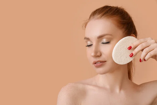 Beautiful woman with makeup sponge on color background