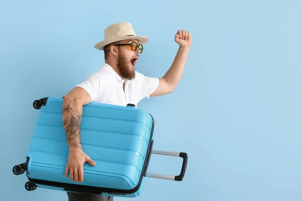 Glücklicher Junger Mann Mit Hut Und Koffer Auf Blauem Hintergrund — Stockfoto