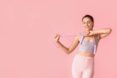 Renkli arka planda ip atlayan genç bir kadın.