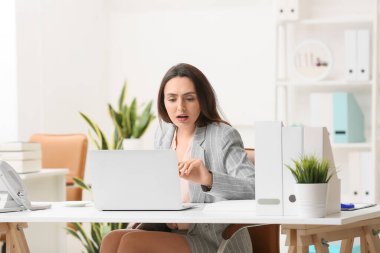 Ofiste dizüstü bilgisayarda çalışan genç sekreter.