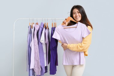 Genç Asyalı kadın ve açık arkaplanda mor tonları olan askılar.