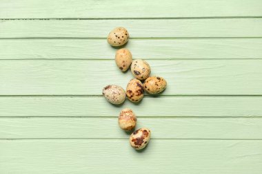 Yeşil ahşap arka planda taze bıldırcın yumurtaları.