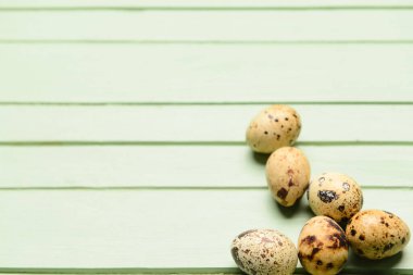 Yeşil ahşap arka planda taze bıldırcın yumurtaları.