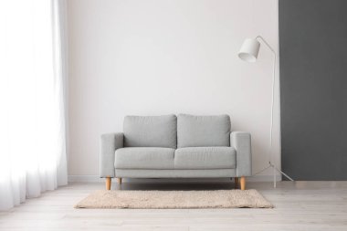 Beyaz duvarın yanında şık bir kanepe ve lamba