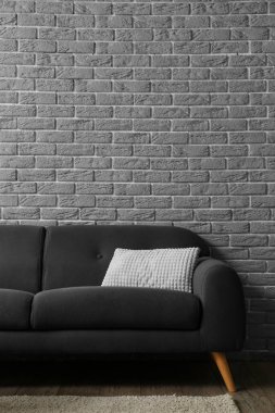 Gri tuğla duvarın yanındaki şık kanepe
