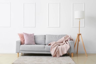 Beyaz duvarın yanında şık bir kanepe ve lamba