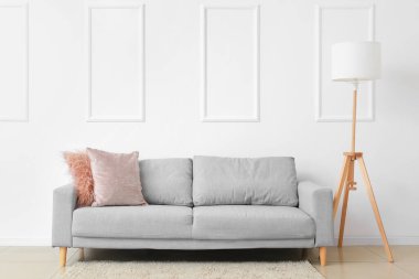 Beyaz duvarın yanında şık bir kanepe ve lamba