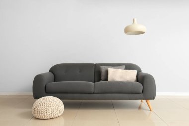 Şık bir kanepe ve ışık duvarının yanında puf.