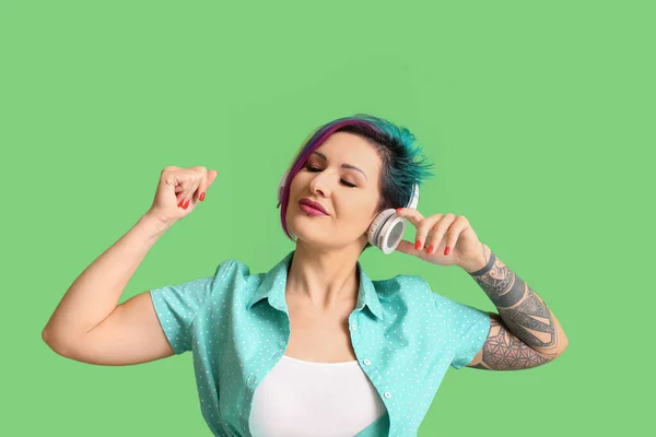 緑の背景で音楽を聴く珍しい髪を持つ美しい女性 — ストック写真