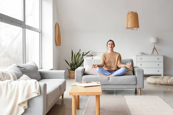 stock image Beautiful young woman meditating on couch at home