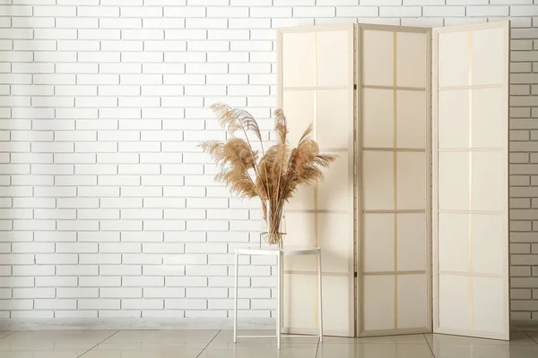 Stylish Folding Screen Reed Branches Table Light Brick Wall Room — Stock Photo, Image