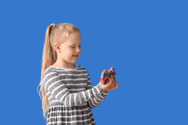 小さな女の子とともに異なるポップそれフィジェットおもちゃ上の色の背景 — ストック写真
