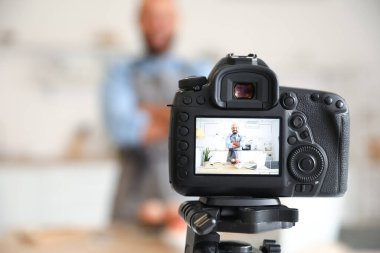 Lezzetli şeftalili kekleri olan yakışıklı adam mutfaktaki fotoğraf makinesinin önünde, yakın plan.
