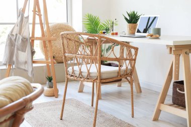 Laptop ve hasır koltuklu modern işyeri