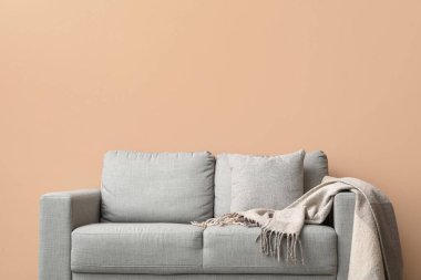 Bej duvarın yanında ekoseli rahat bir kanepe.