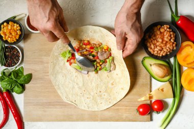 Adam lezzetli bir burrito hazırlıyor.