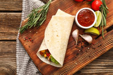 Ahşap zemin üzerinde et ve sos olan lezzetli burrito.